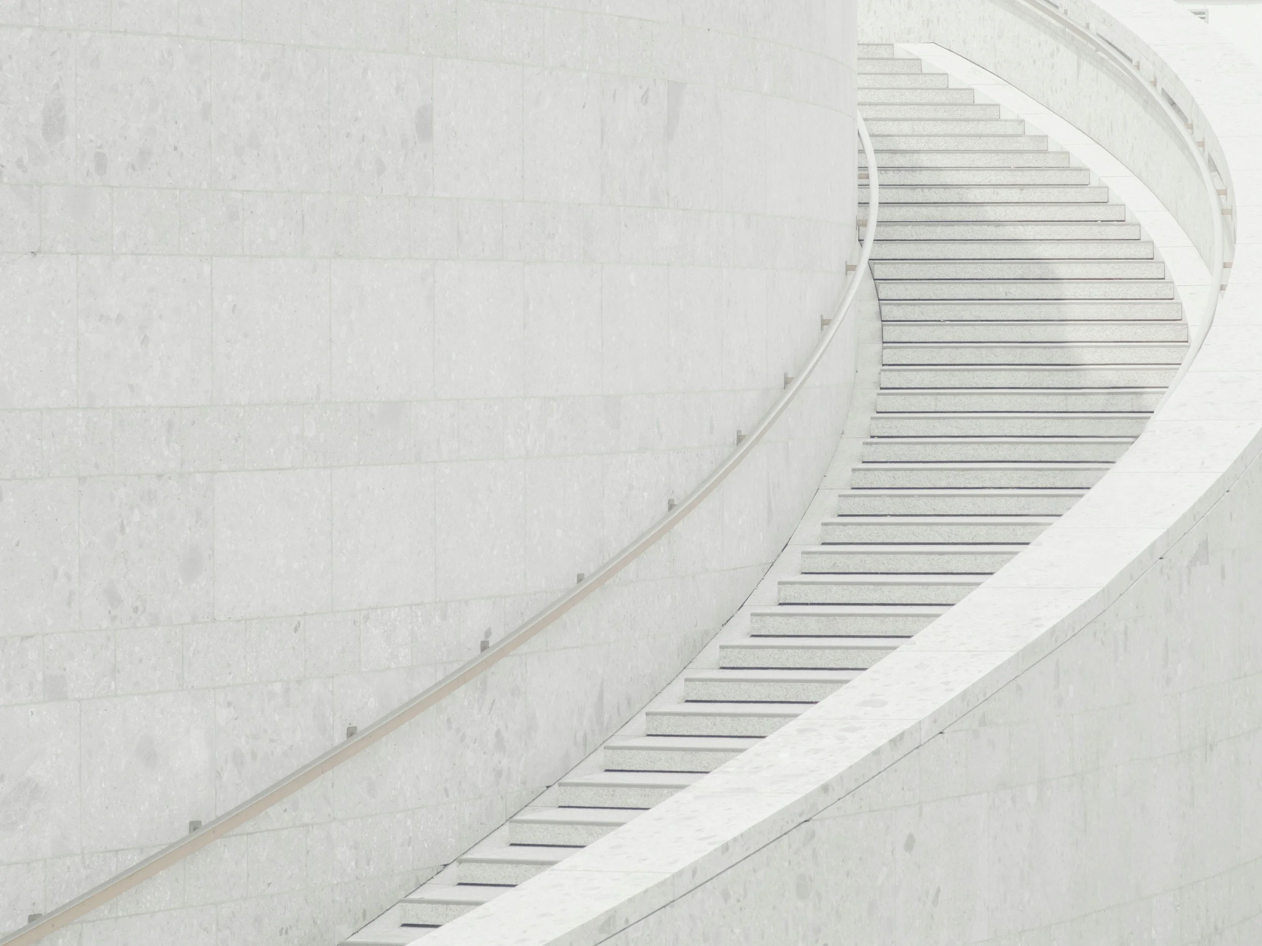 White marble staircase with a curved white handrail, symbolizing moving up in the world with Alpha Consulting