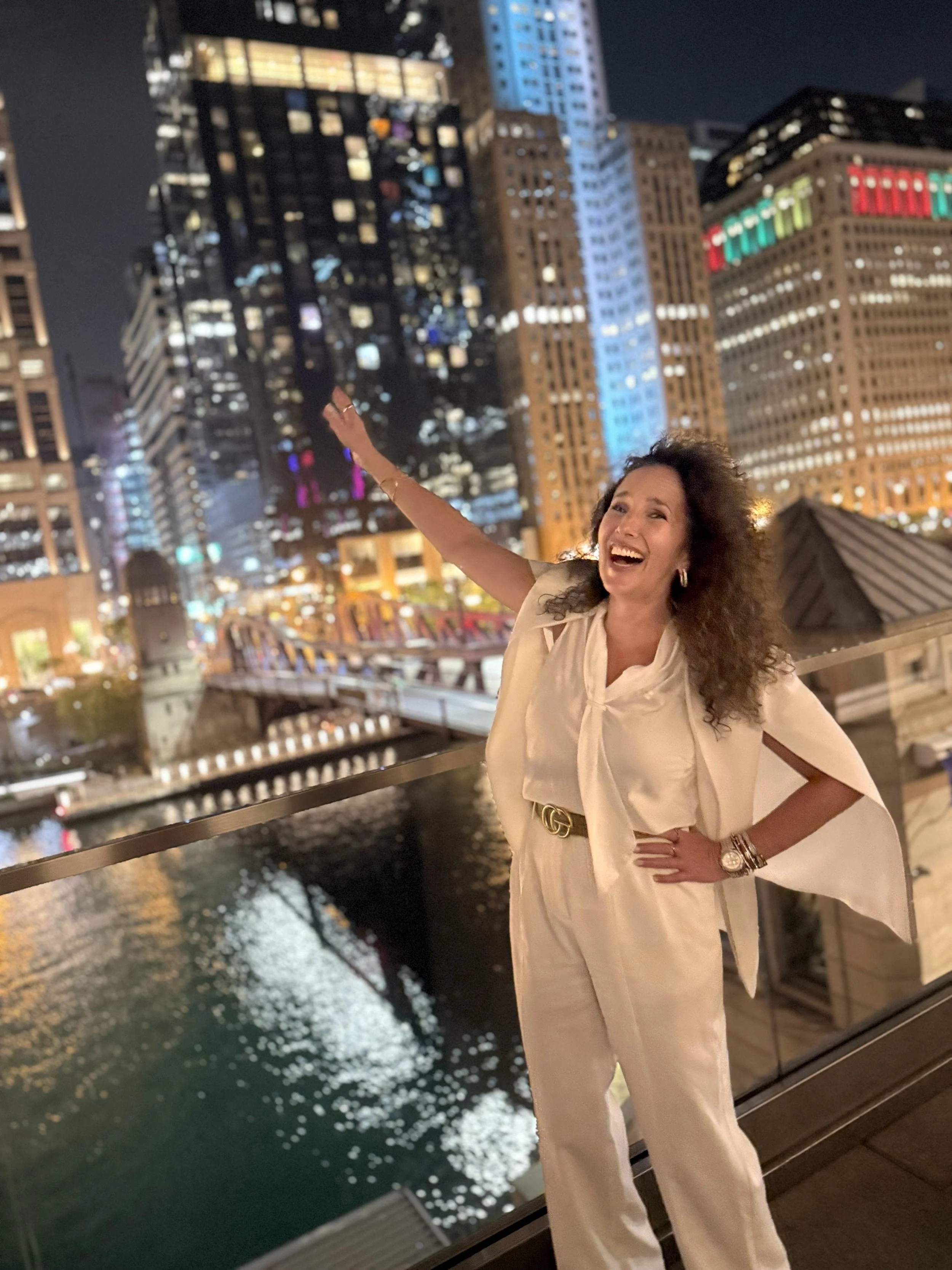 Career Coach and Confidence Creator Aimee Cohen of Alpha Consulting standing in front of the Chicago skyline at dusk in an enthusiastic pose