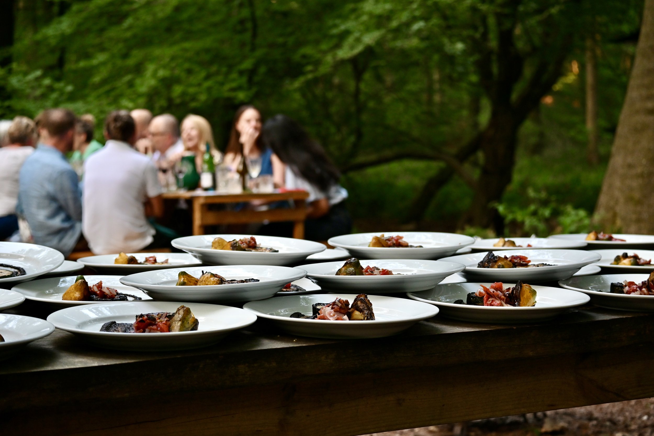 diners eating and drinking at outdoor woodland feast Chilterns