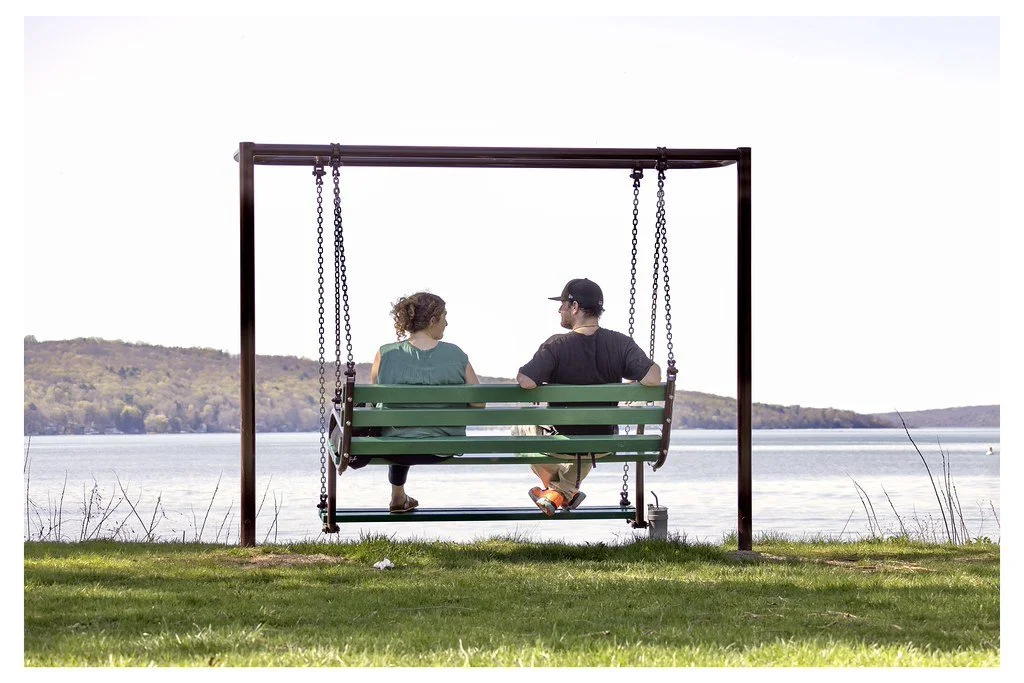 Couple Audrey Schultz, left, and Lucas Kline, sit on a swing bench overlooking Cayuga Lake at Stewart Park in Ithaca, New York