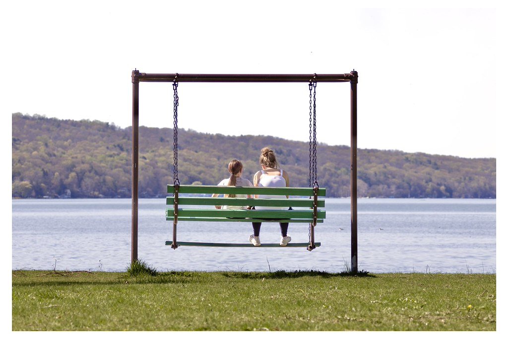Izzy O’Connor, left, and her mother Grace O’Connor, sit on a swing bench overlooking Cayuga Lake at Stewart Park in Ithaca, New York. 