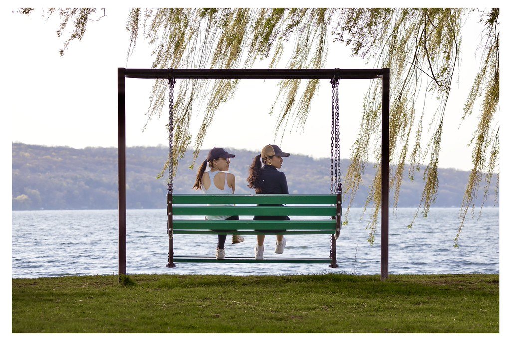 After a walk at Stewart Park, friends Brie Huang, left, and Ava Sato, rest on a swing bench in Ithaca, New York. 