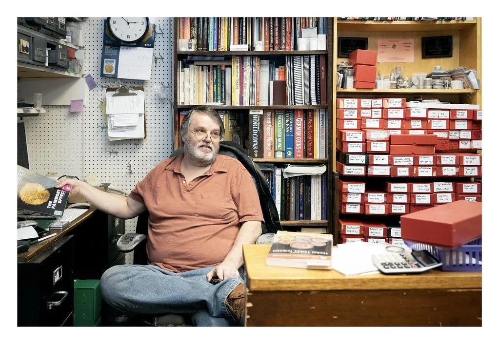 Robert Lisk, owner of Cayuga Coins, reads at his desk during his lunch break at DeWitt Mall in Ithaca, N.Y. Lisk has operated the business for five years but has been collecting coins since childhood.