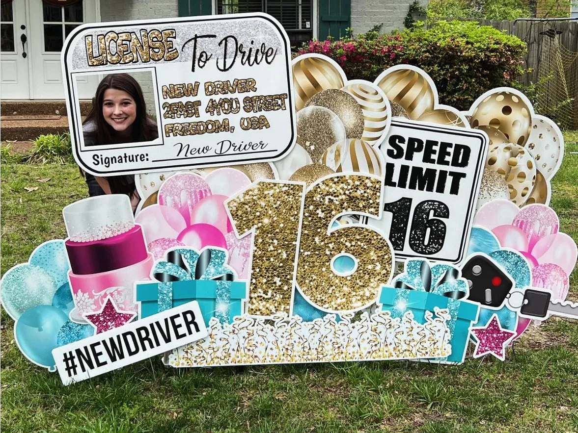 Decorative yard sign celebrating a new driver's license with a large gold glitter number 16, surrounded by balloons, gifts, and a fake photo ID of a smiling girl. The sign includes a speed limit sign, hashtag #NEWDRIVER, and a space for a signature.