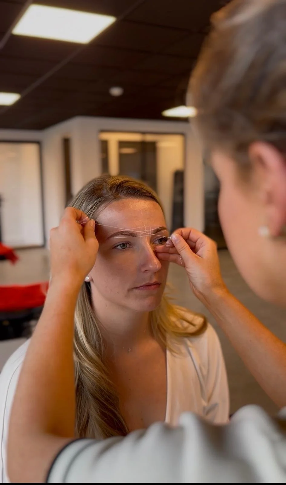 Een vrouw ondergaat een micro-needling behandeling op haar voorhoofd in een kliniek, terwijl een specialist de procedure uitvoert.