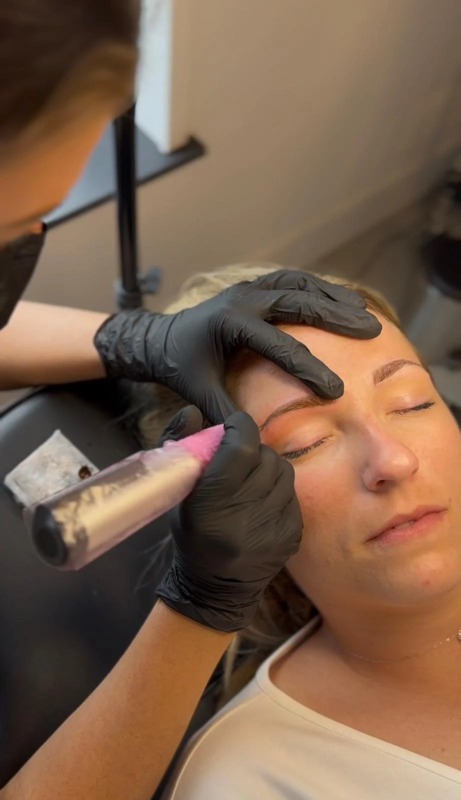 Persoon krijgt permanente make-up op wenkbrauwen door een schoonheidsspecialist in een salon.