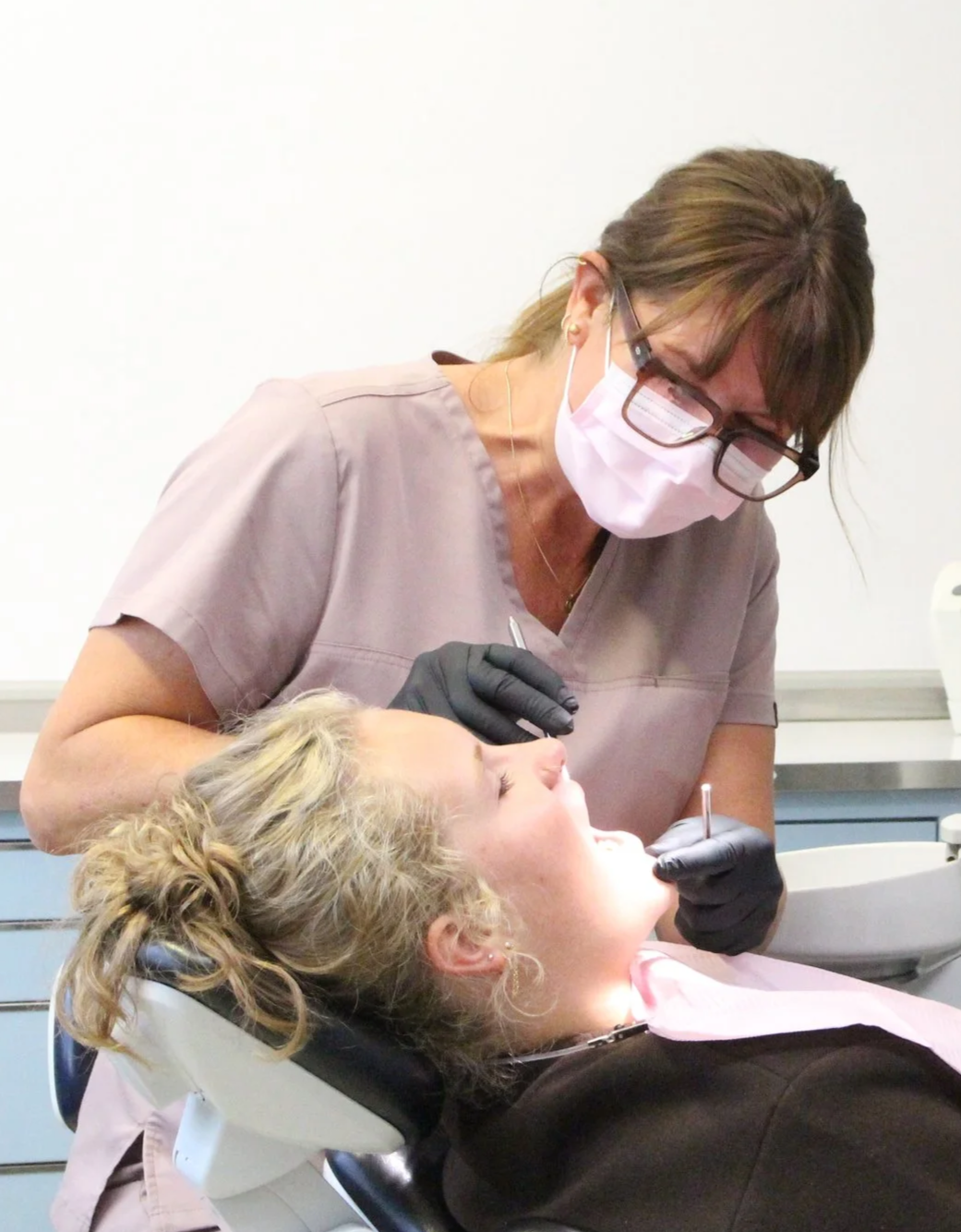 Zahnärztin untersucht Patientin im Behandlungsstuhl im Dentalbüro.
