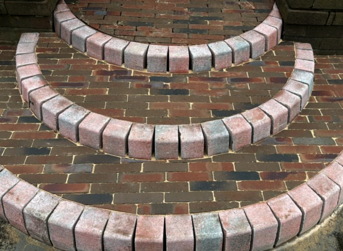 Three curved brick benches with a brick pavement underneath.