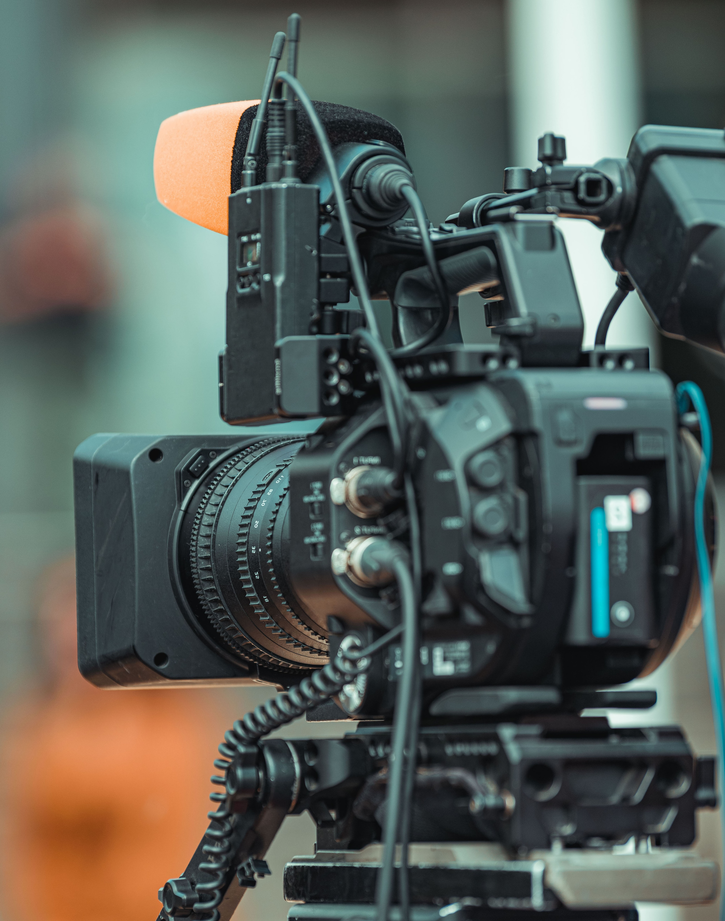 Close-up of a professional video camera with a microphone attached, set up on a rig, ready for filming.