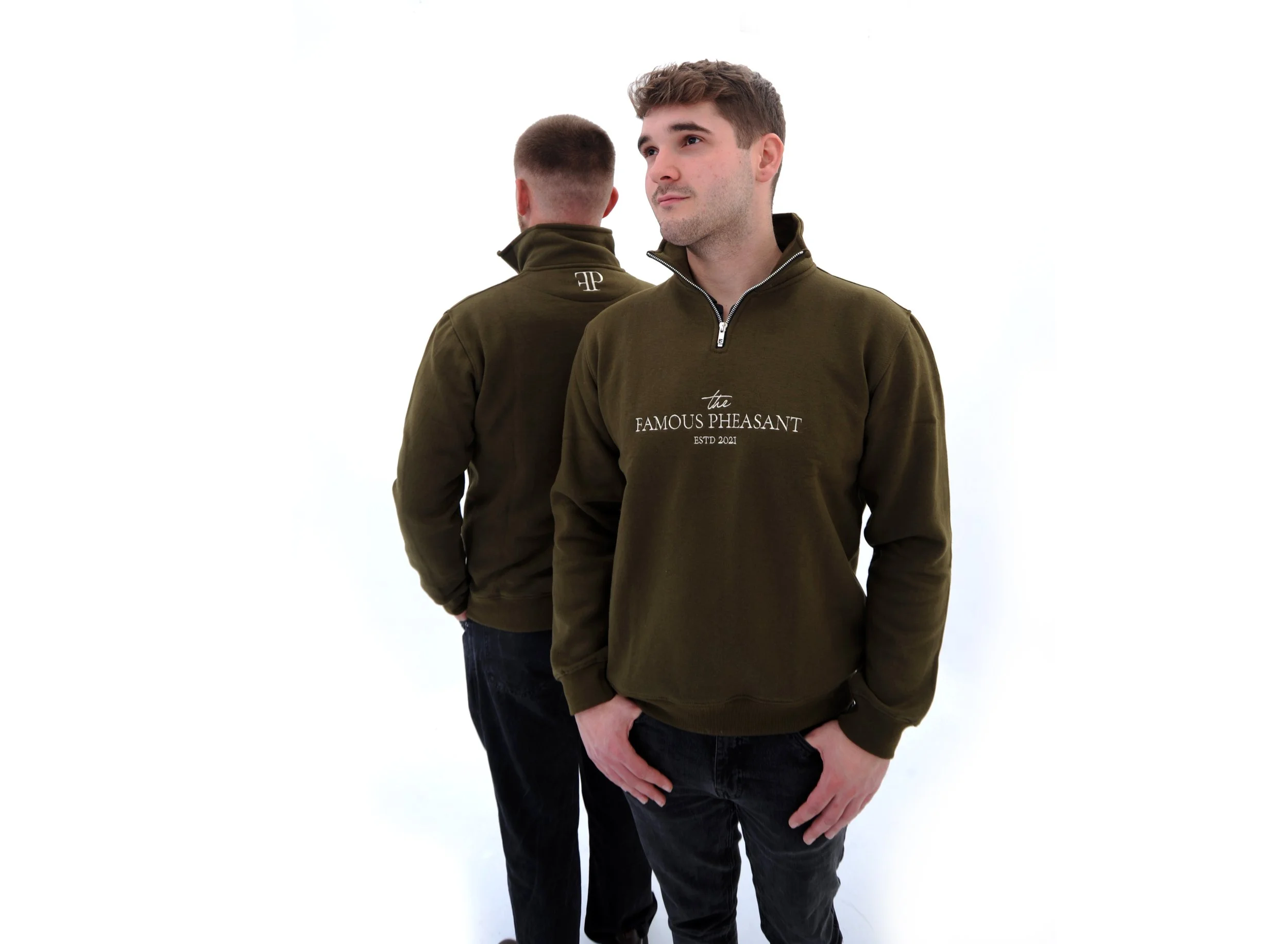 Two young men standing against a white background, wearing matching olive-green sweatshirts with the words "the FAMOUS PHEASANT" on the front. One man is facing forward with his hand on his hip, and the other has his back turned, showing a logo on th