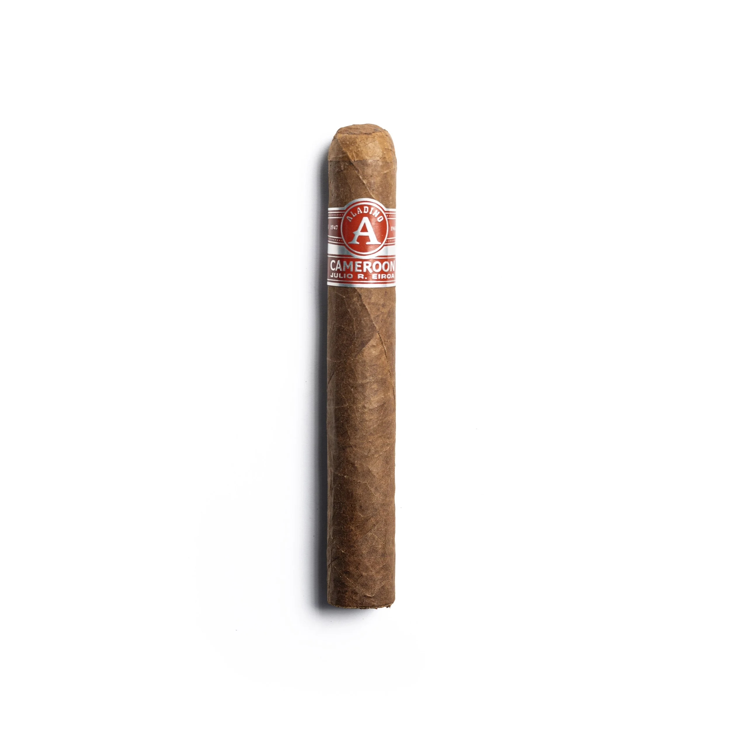 A single cigar with a red and white band that reads "Aladino Cameroon" and "Julio R. Eiroa" is positioned vertically on a white background.