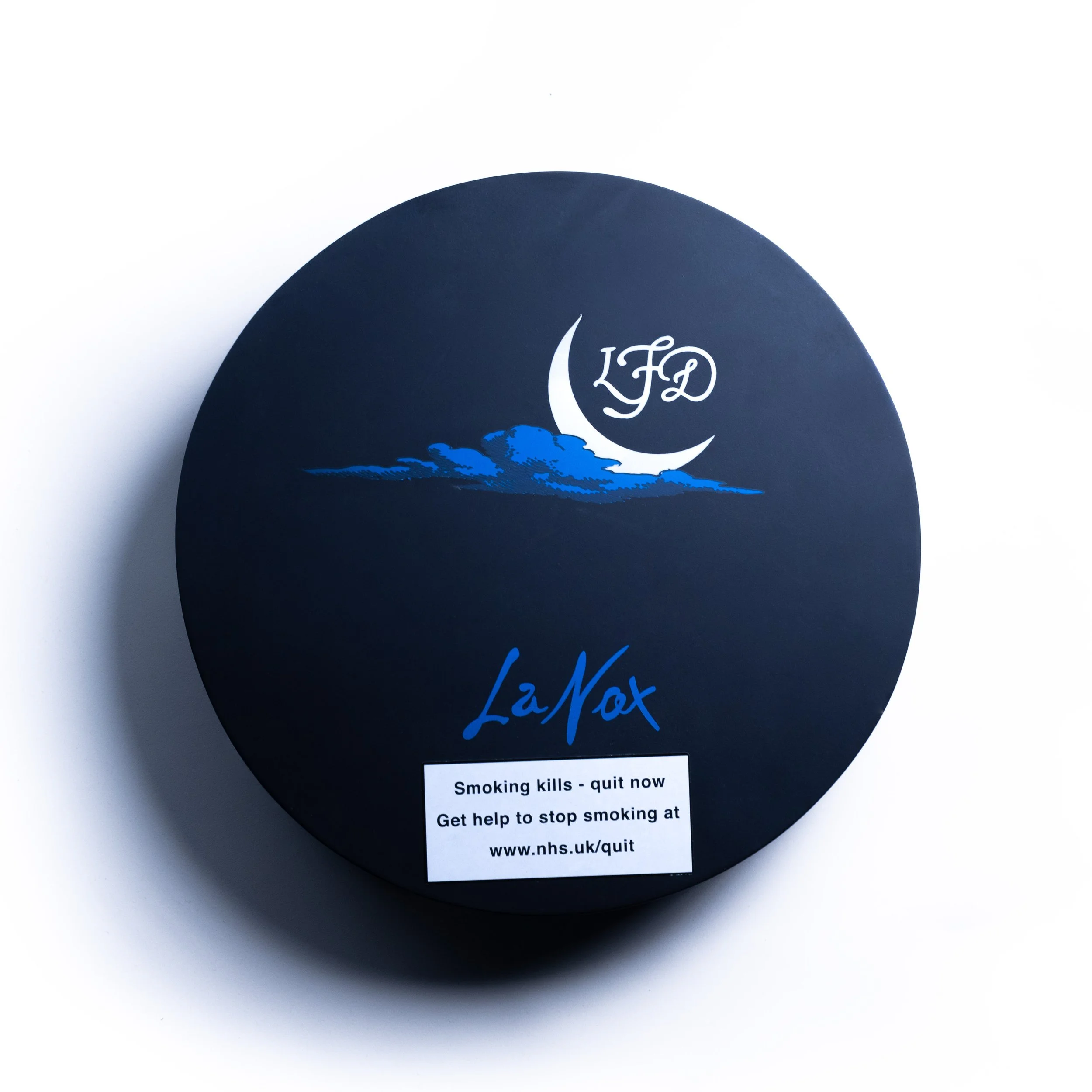 A circular black sign with white and blue text and graphics promoting quitting smoking. The sign features a crescent moon and cloud design with the acronym 'LAD' and a URL for quitting support.