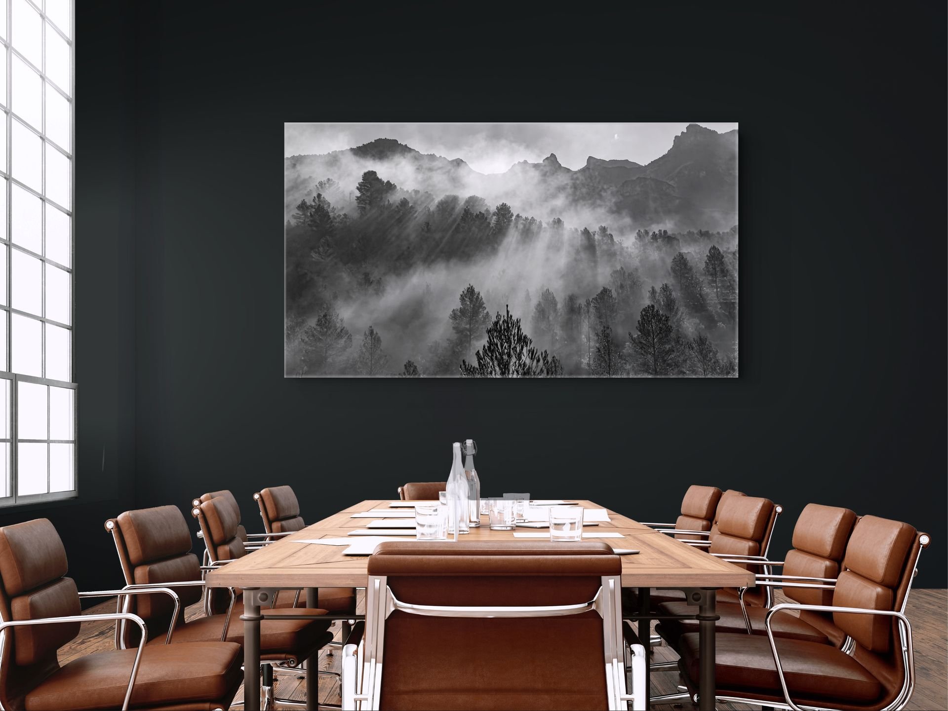 Black-and-white forest landscape print in a dark, minimalist office boardroom