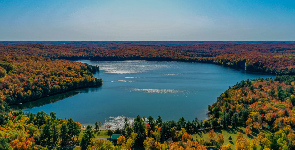 Aerial view of Lake of Bays, ON surrounded by colorful autumn trees in fall.