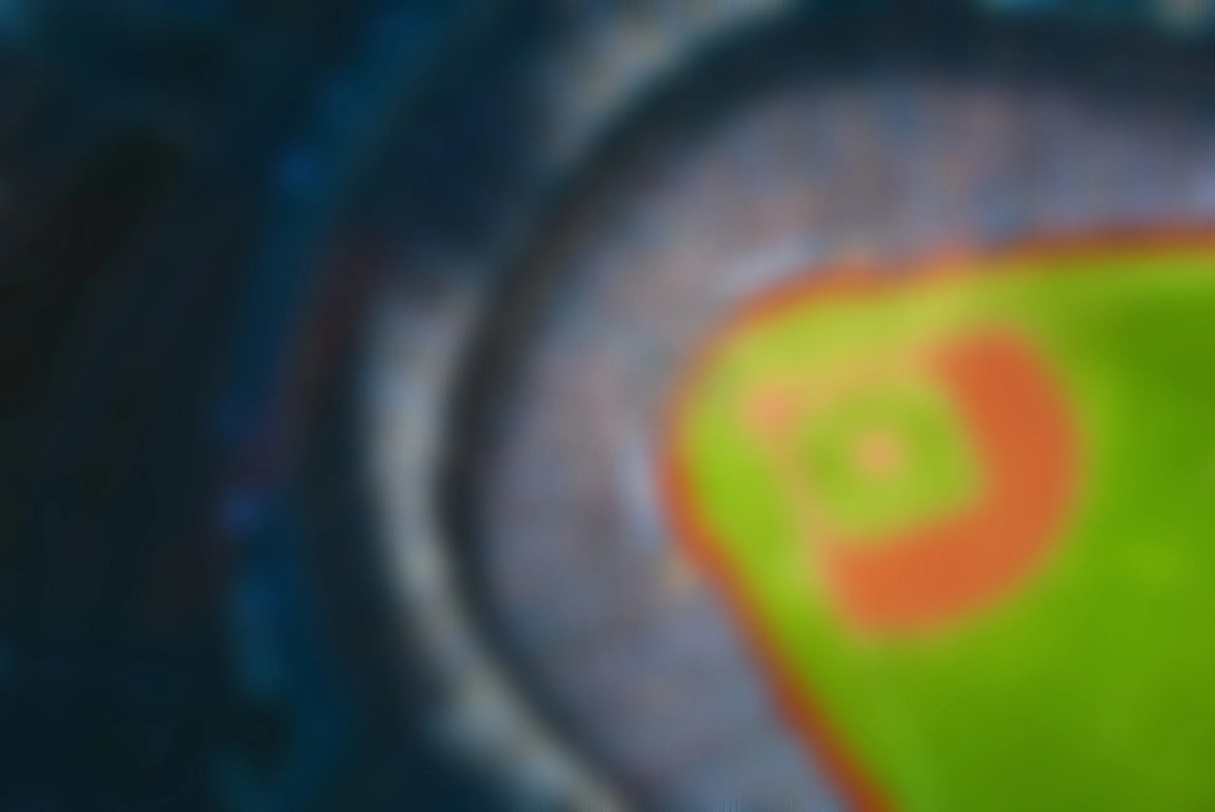 A blurry image with a swirl of bright colors including green, orange, and yellow, against a dark background.