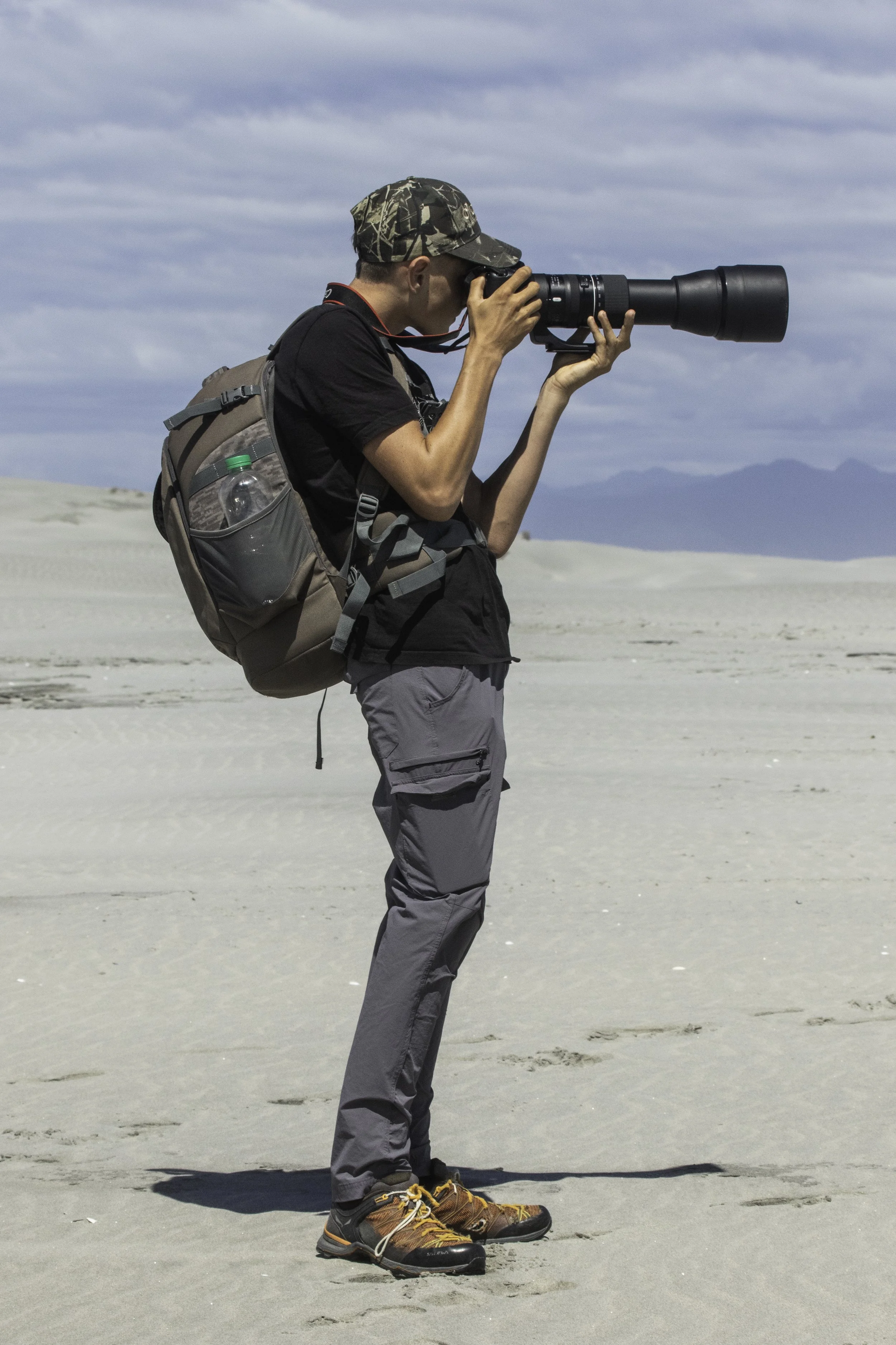 Sam Moynan stands on Farewell Spit capturing images of migratory waders.