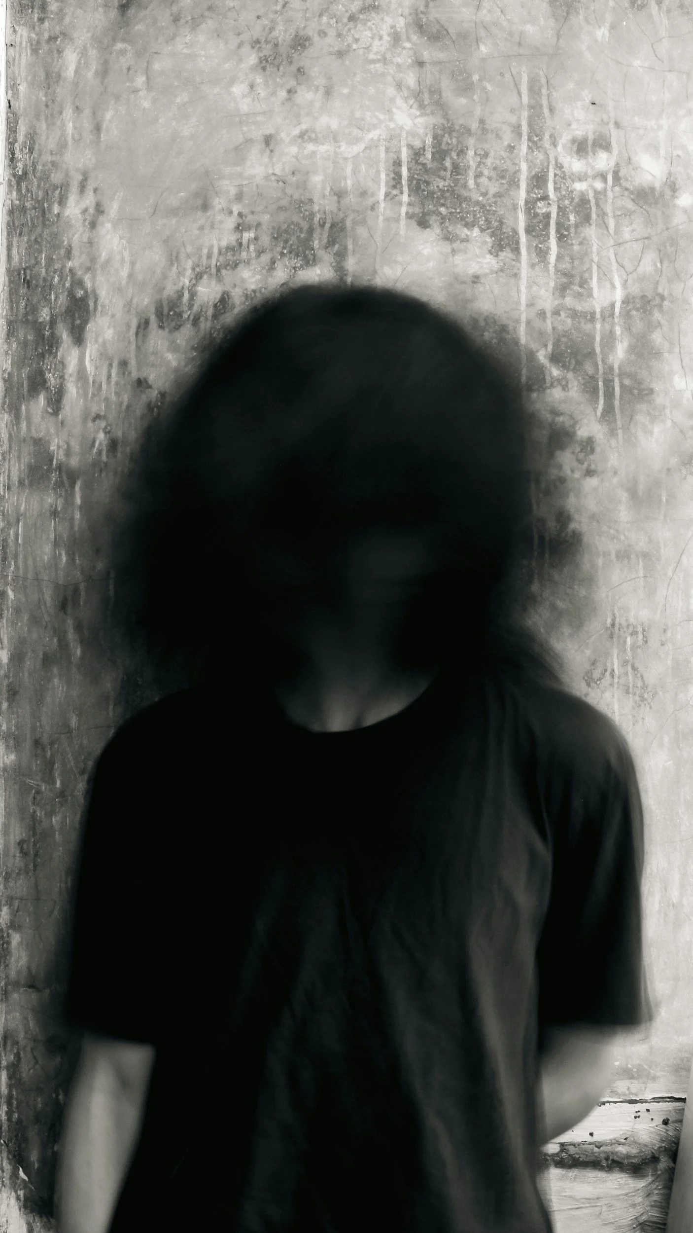An image of a person in a black tshirt with a black cloud over their face.