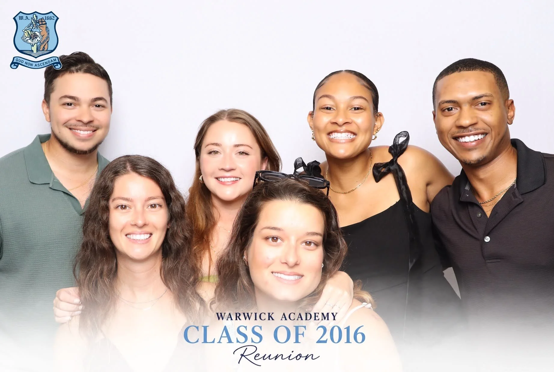 Group of six young adults posing together at the Warwick Academy class of 2016 reunion, smiling in front of a white background with the event title, with a custom graduation photo booth frame