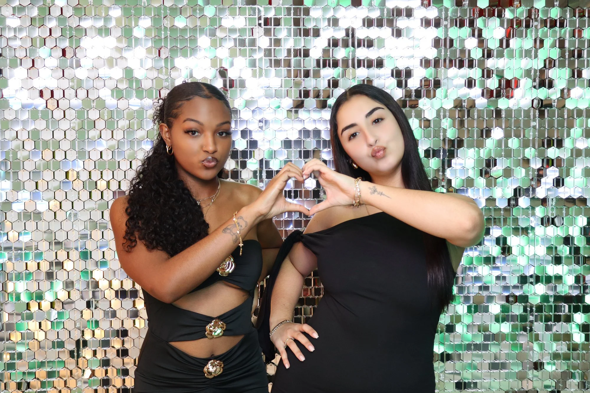 Two guests posing in front of a silver sequin backdrop at a Reflections Photo Booth event