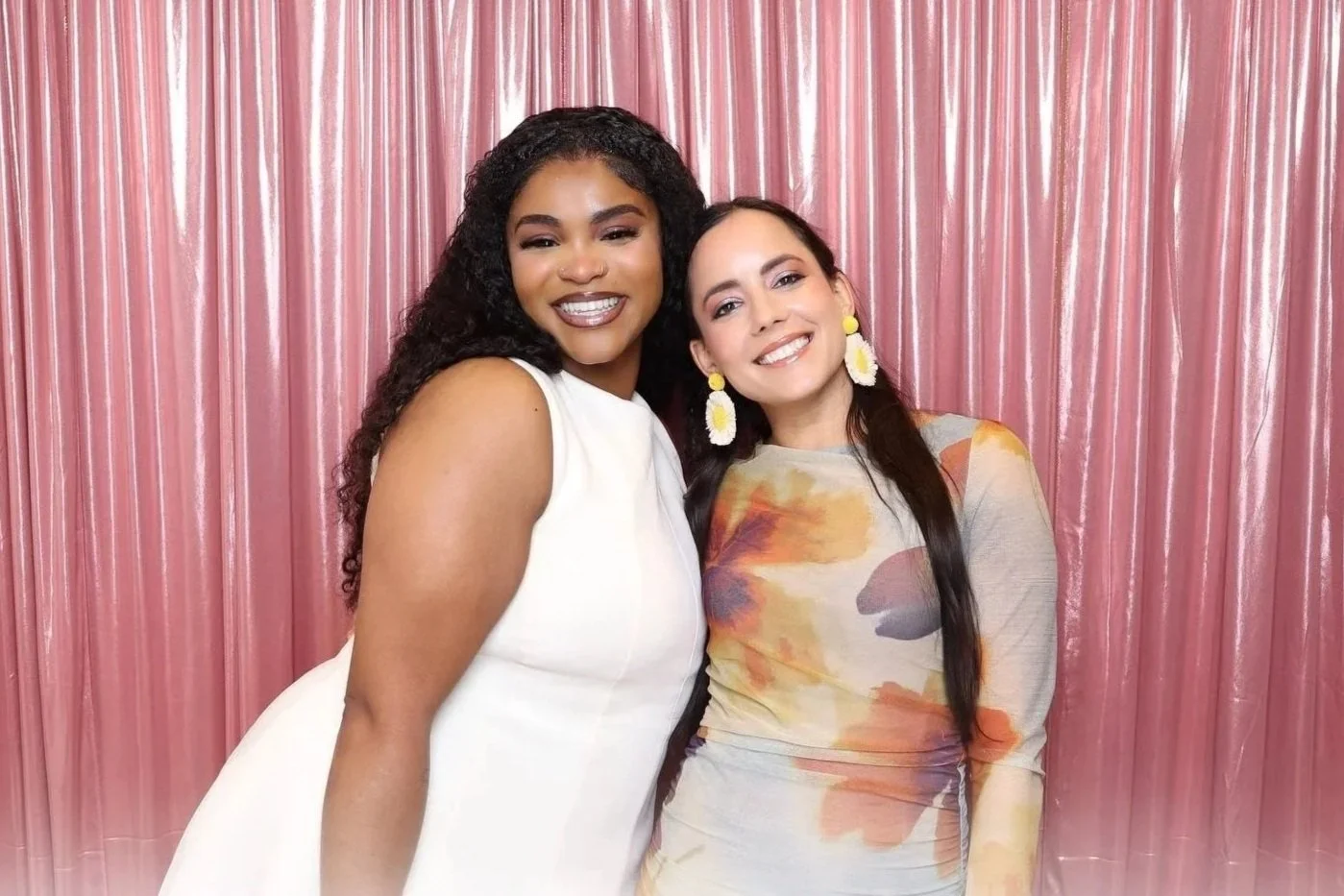 Two guests posing together at Bermuda event, in front of a metallic pink backdrop