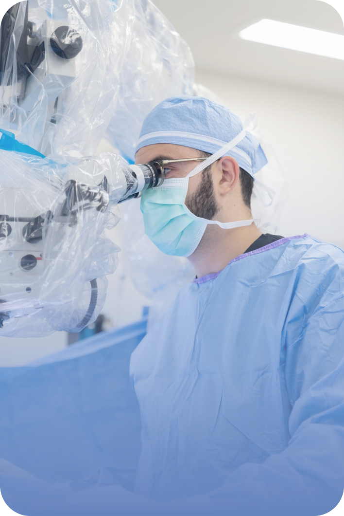 Dr. Hassan A. Fadel operating at a surgical microscope