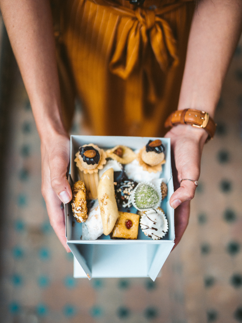 Person holding a box of assorted cookies and sweets
