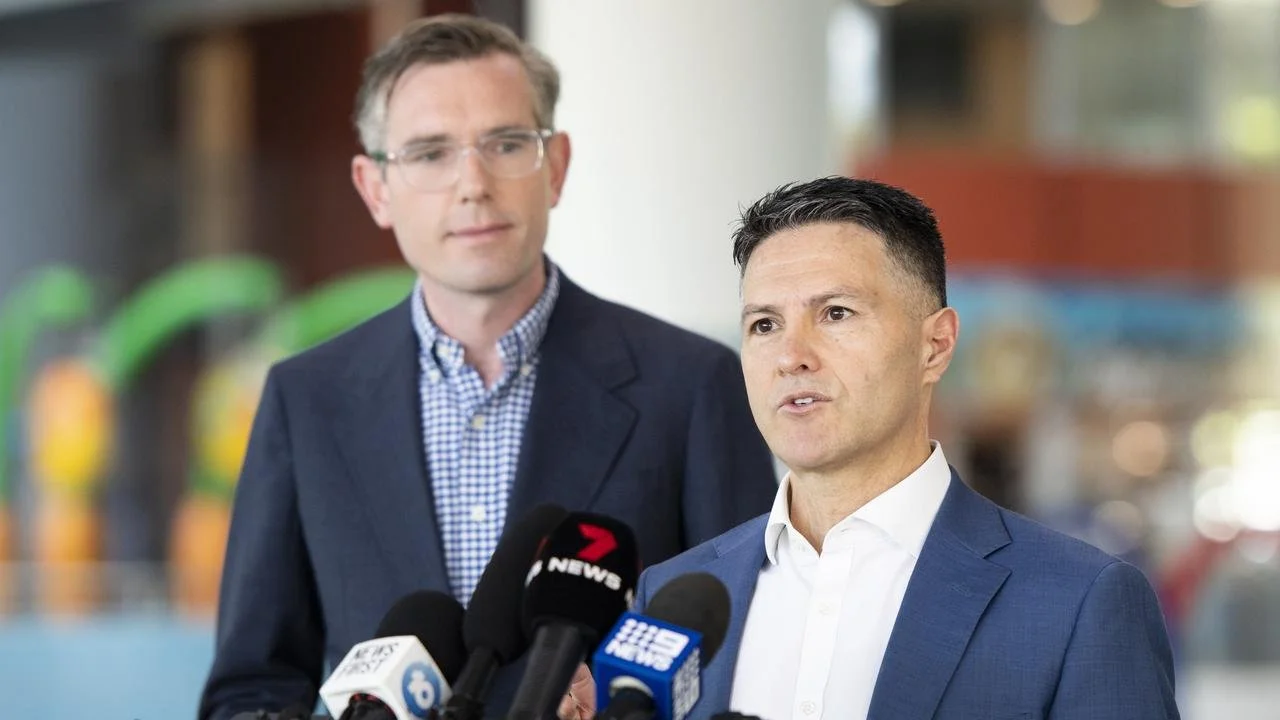 A photo of former Liberal gaming minister Victor Dominello speaking at a microphone, next to former Liberal Premier Dominic Perrottet