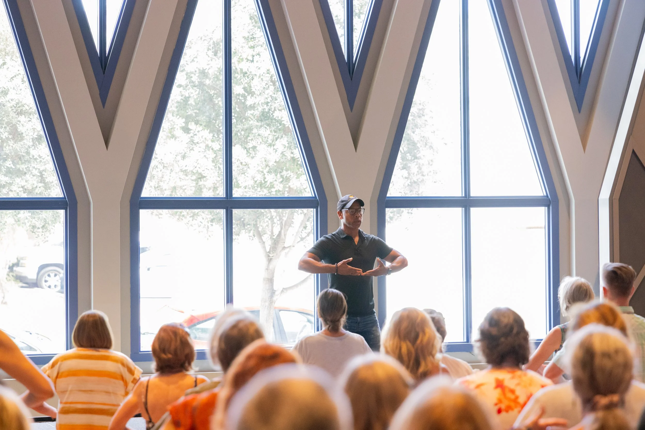Steven Washington speaking to a seated audience in a bright, windowed room.
