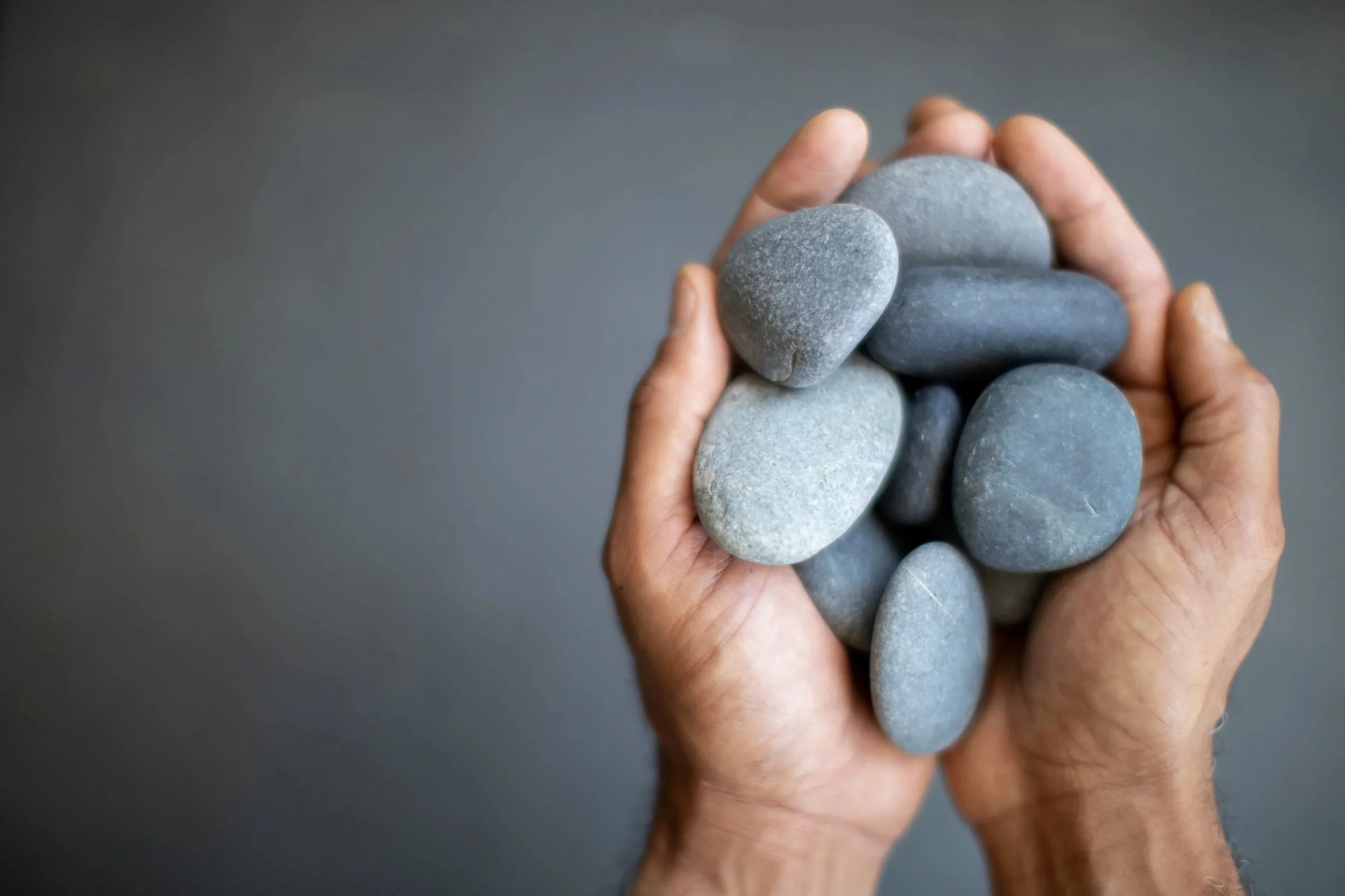 Steven's hands holding smooth stones, representing the Foundations coaching package