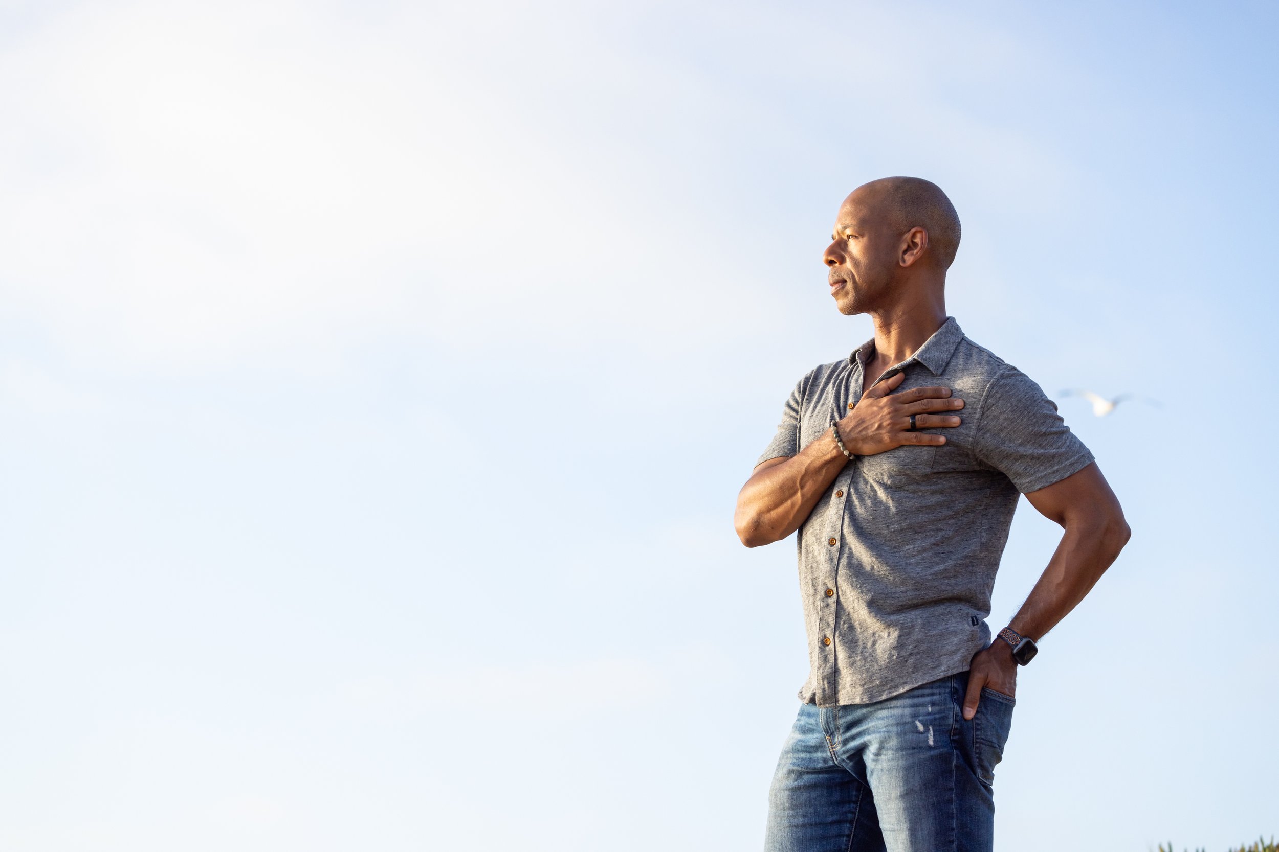 Steven Washington, standing outdoors with his hand over his heart, gazing into the distance.