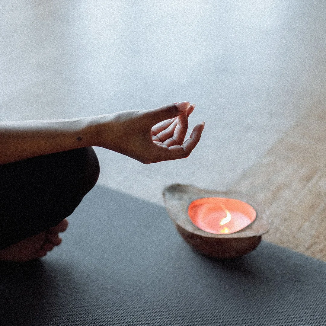 Close-up of hands near a lit candle, symbolizing the calming Weekly Reset practice.