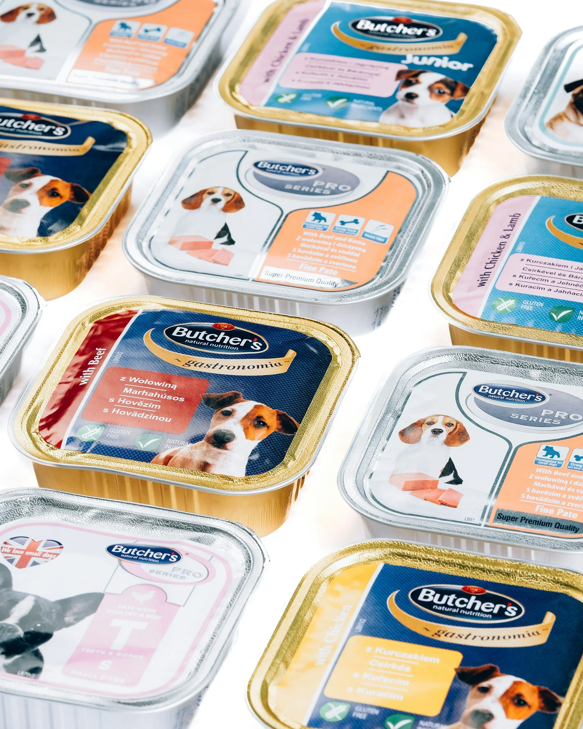 Variety of Butcher's dog food containers with labels indicating flavors and product details, featuring images of dogs.
