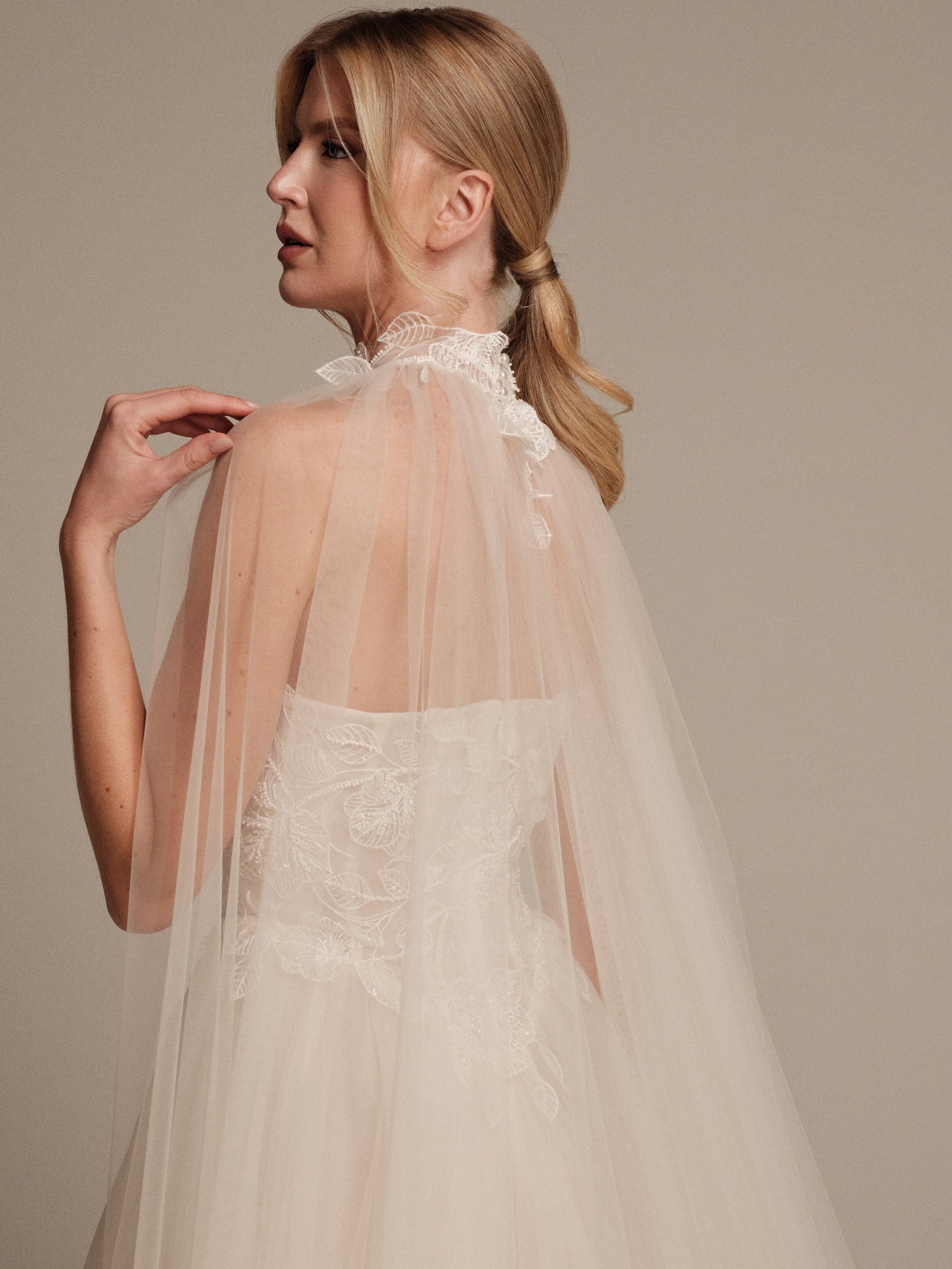 Luna bridal cape featuring delicate lace detailing at the neckline by Maria Pia