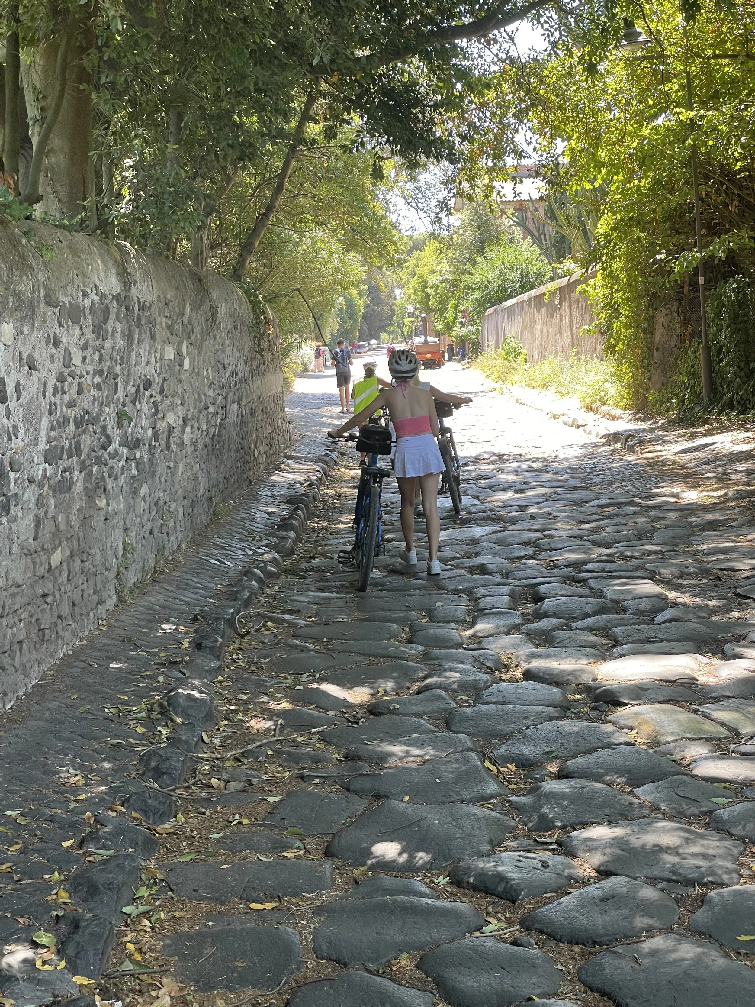 cyclists walking bicycles across the original cobblestones of the Ancient Appian way