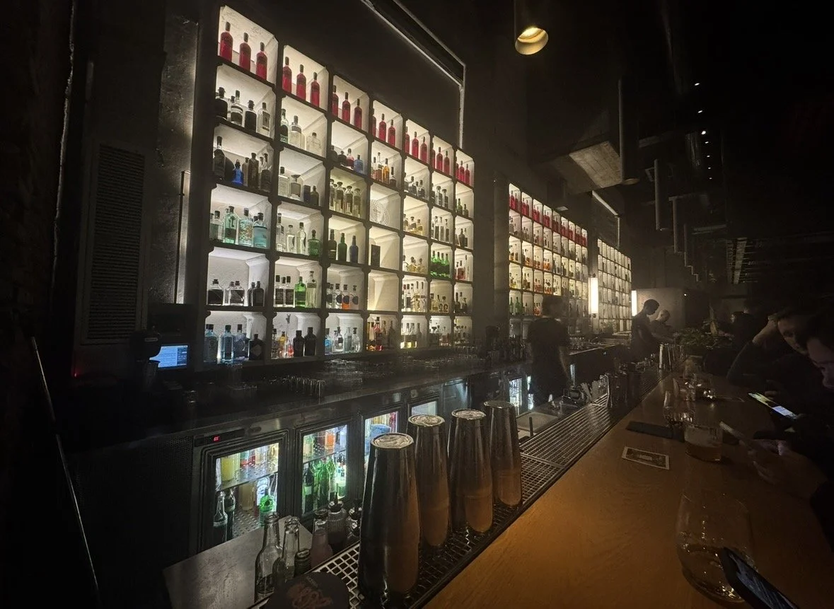 Backlit bottle wall and cocktail bar at Moebius Milano