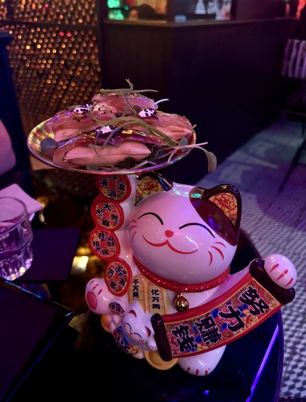 Bao buns served on lucky cat statue at Salmon Guru Madrid