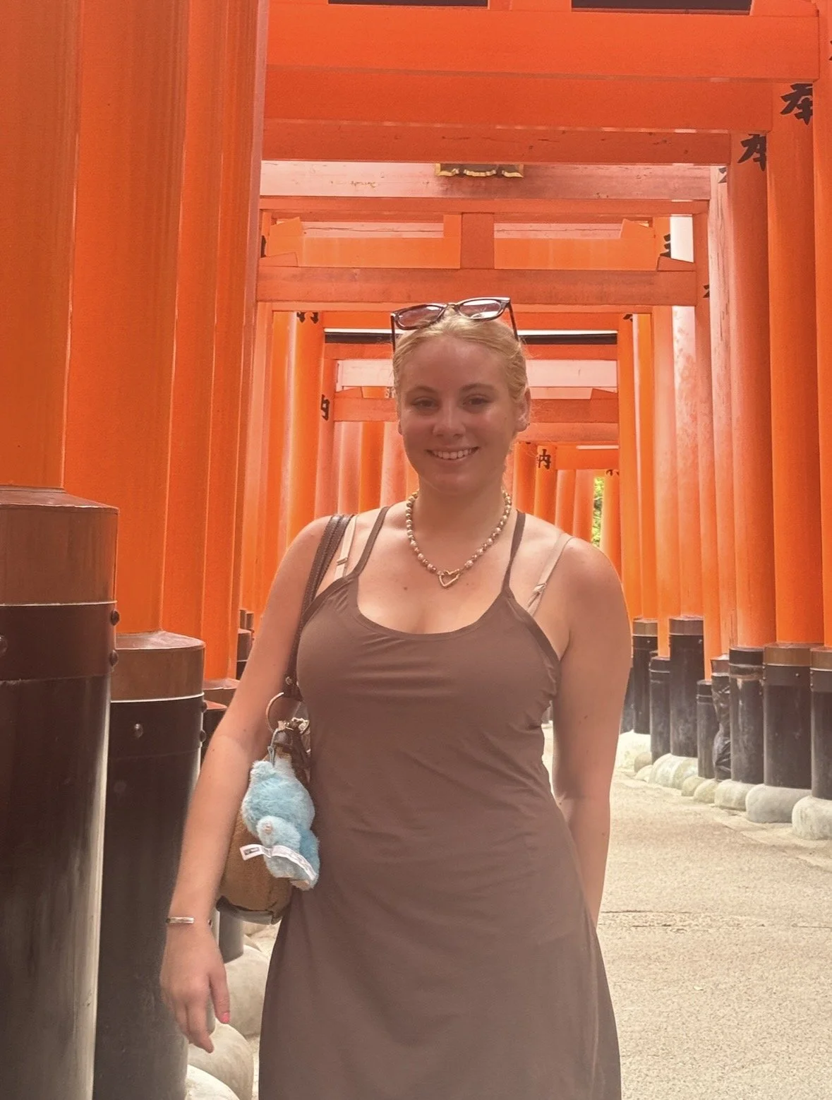 Visitor standing beneath the iconic vermilion torii gates at Fushimi Inari Taisha in Kyoto
