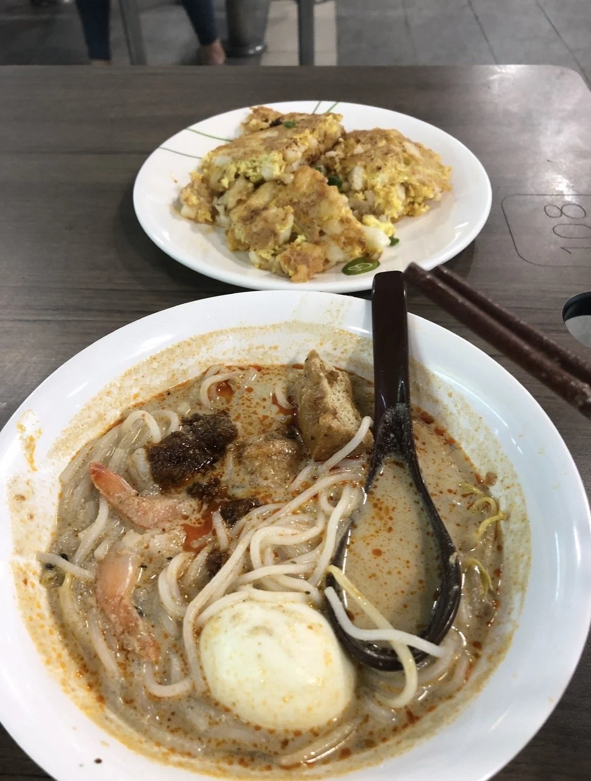 Singapore laksa with prawns and egg alongside fried carrot cake at a local hawker centre