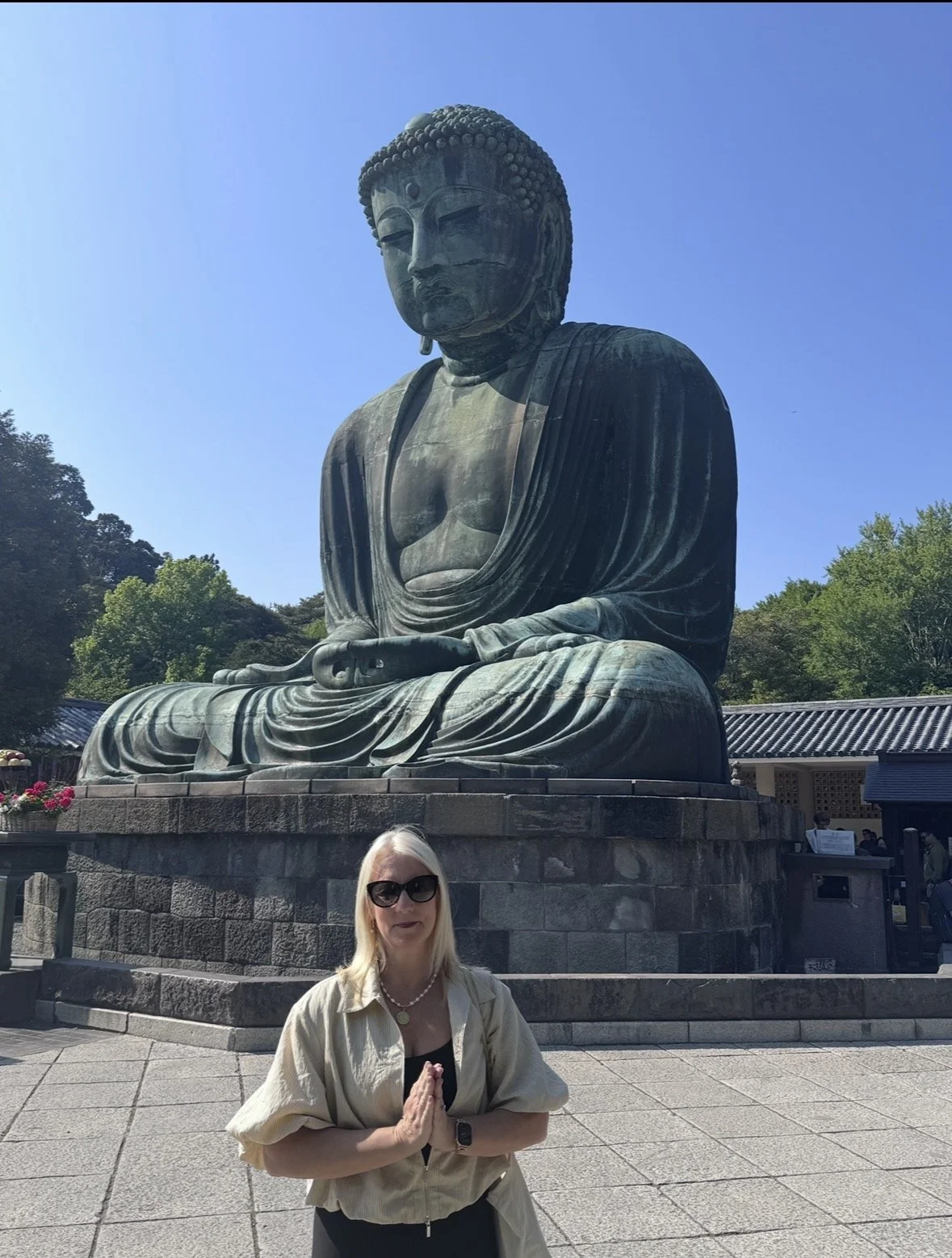 posing in prayer in front of the Great Buddha of Kamakura at Kotoku-in Temple, Japan