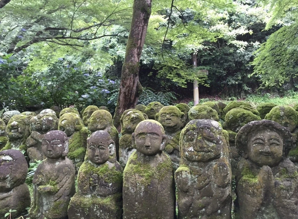 Unique carved stone rakan statues at Otagi Nenbutsu-ji Temple surrounded by lush greenery in Kyoto