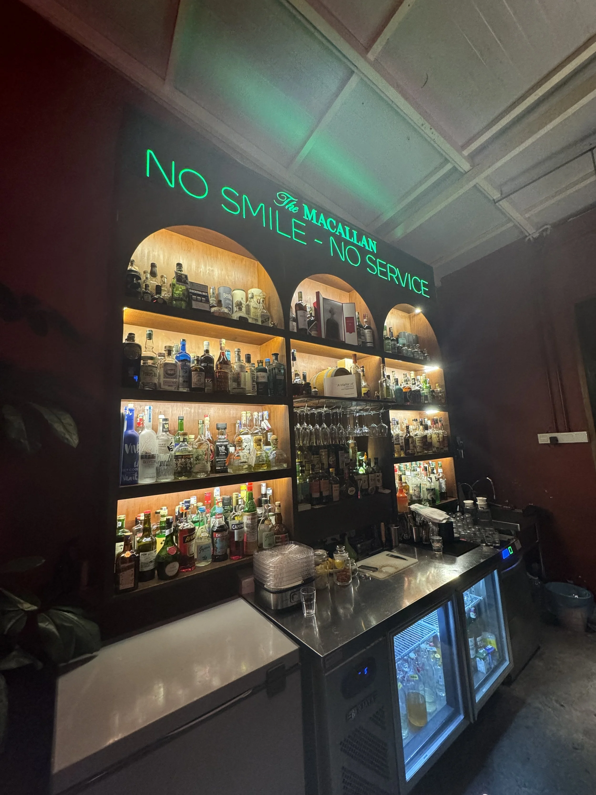 Backdoor Bodega cocktail bar interior with No Smile No Service sign