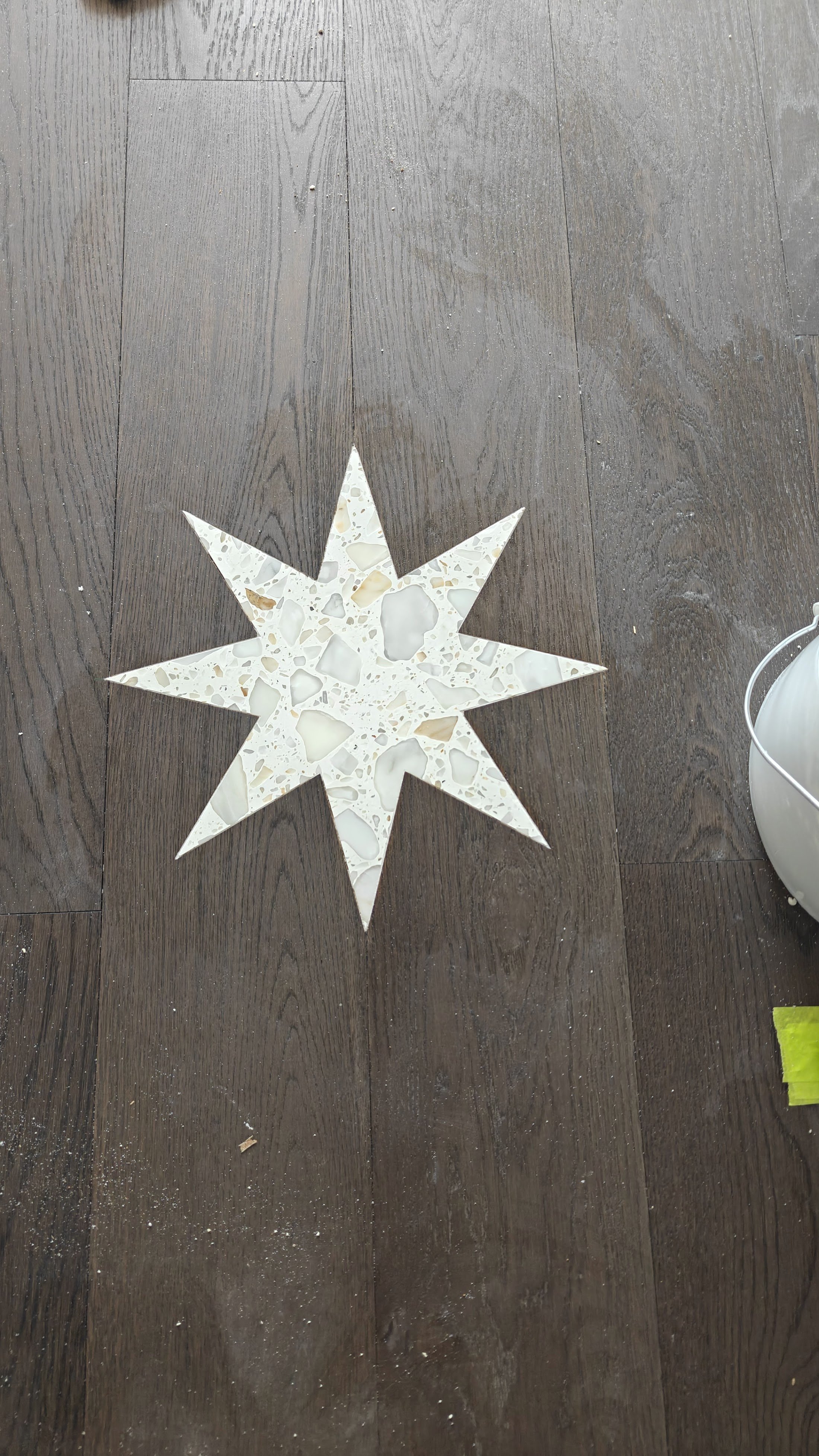 White terrazzo star inlay set into dark wood flooring.