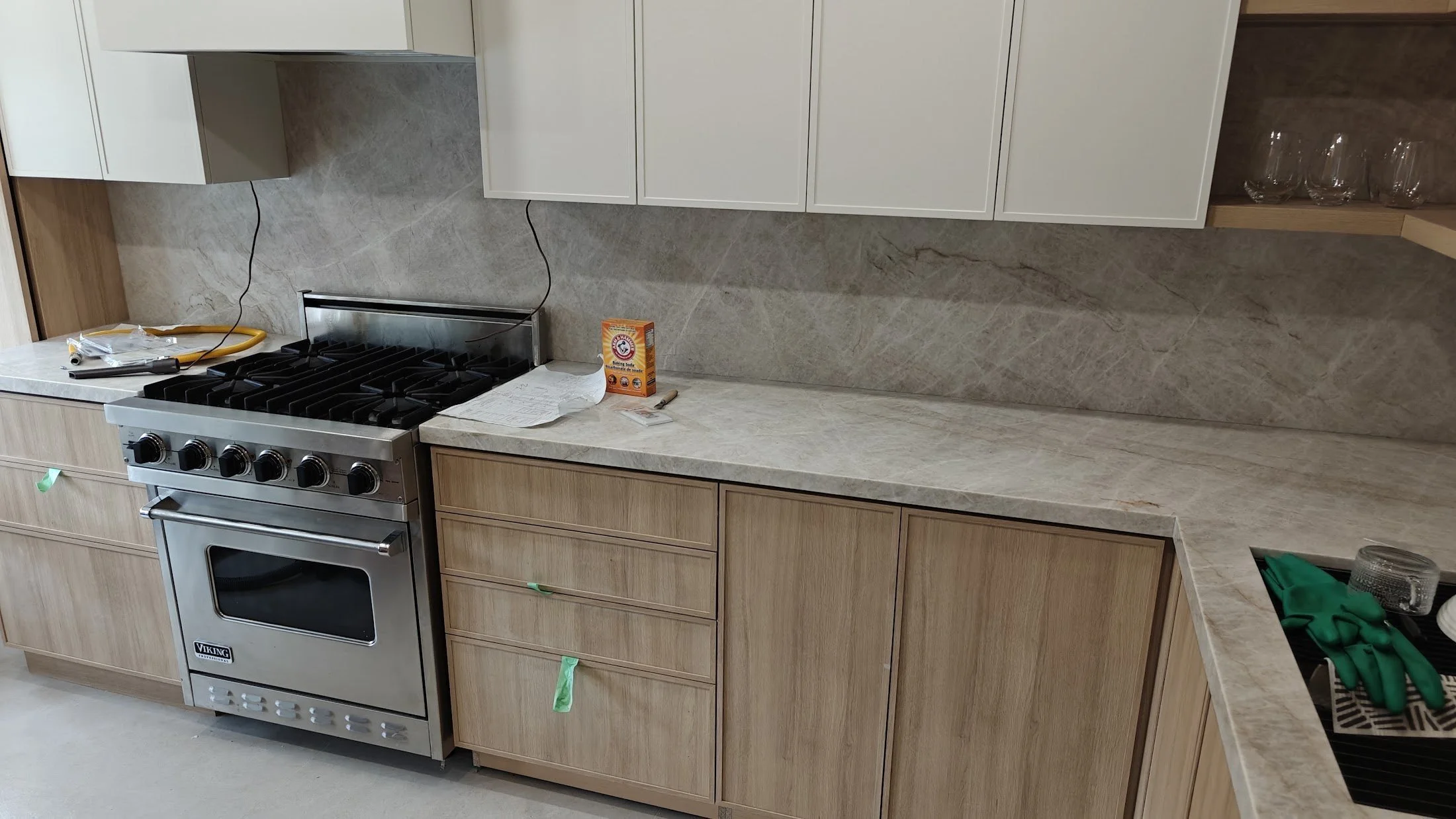 Range wall with wood-grain drawer banks, a stone-look backsplash and counter, and white upper cabinets