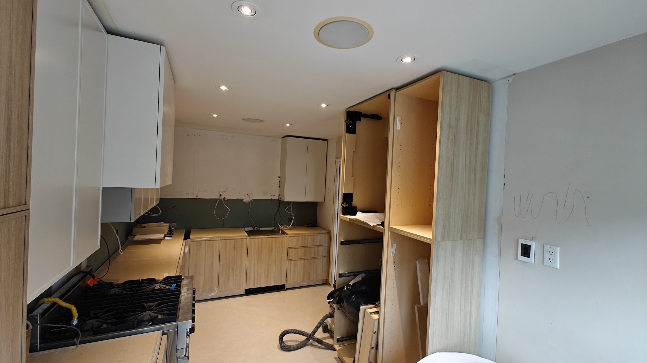 Kitchen with unfinished cabinetry and visible wiring, with ceiling lights turned on.