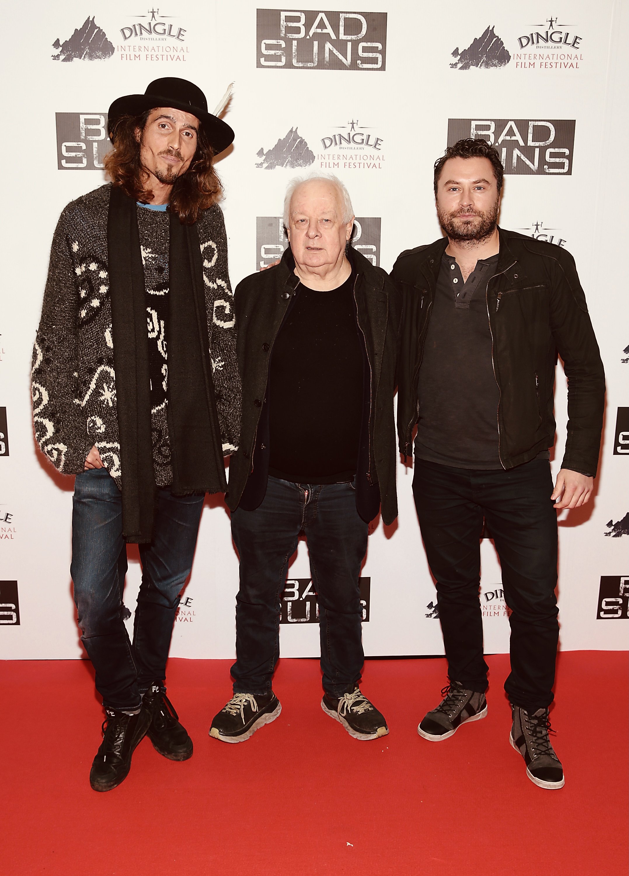 Dylan Townsend, Jim Sheridan & Kevin Ryan on a red carpet at the Dingle International Film Festival, with a backdrop displaying logos for the festival and the film 'Bad Suns'.