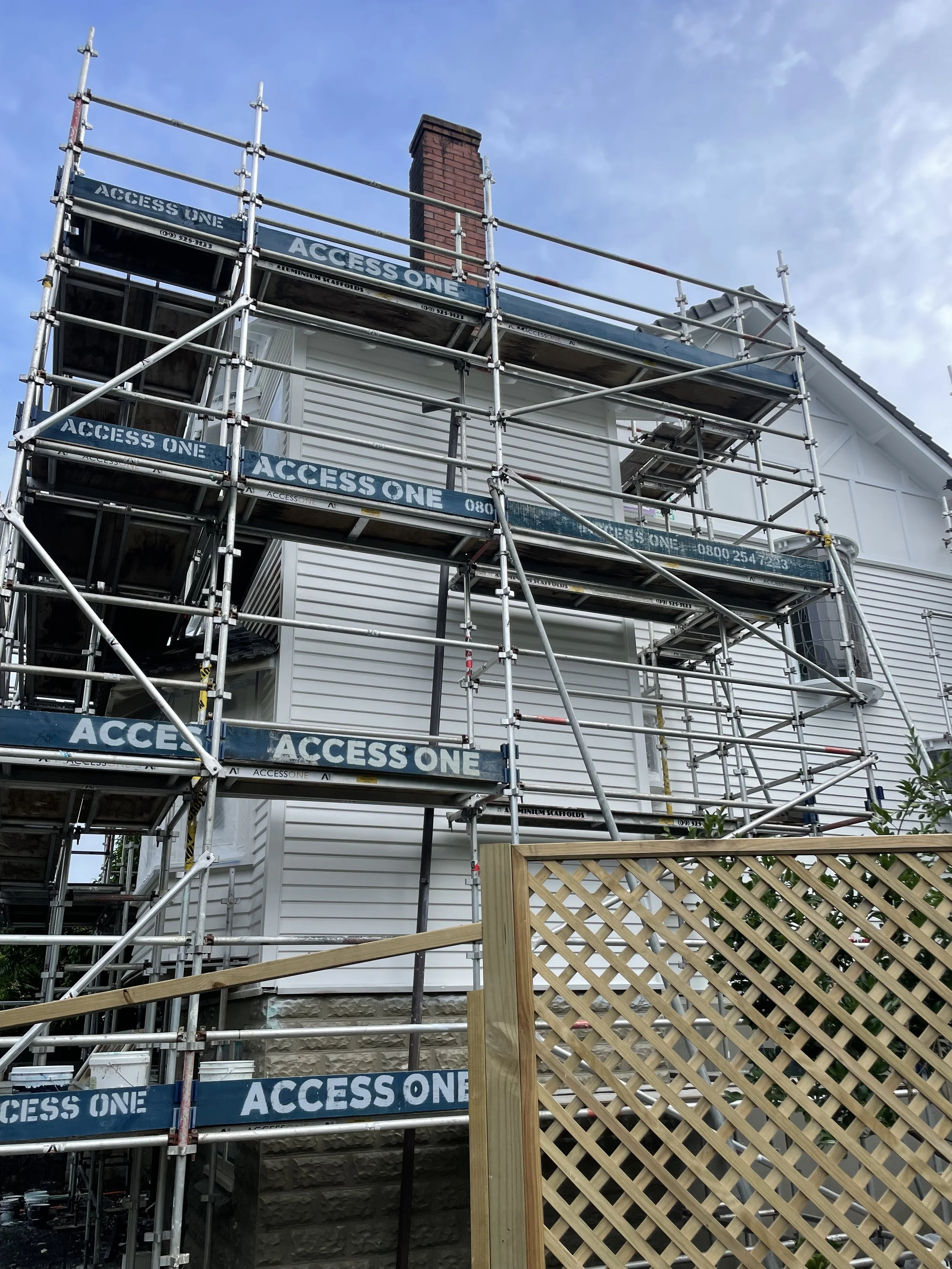 Construction scaffolding around the house with signs reading 'ACCESS ONE'.