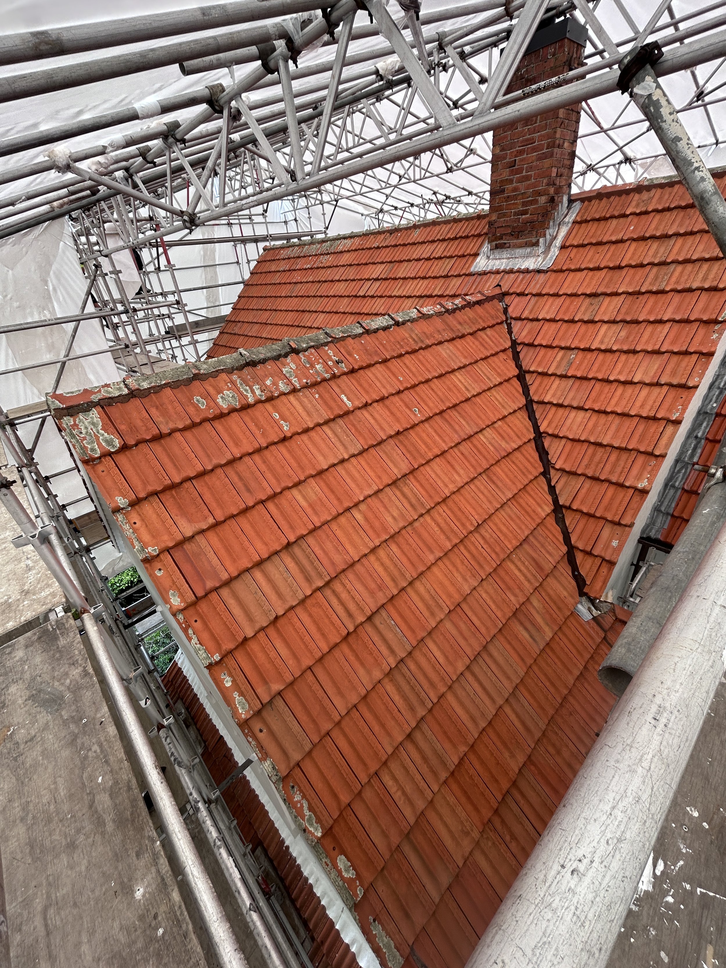 Red-tiled roof of a building under construction or renovation with scaffolding around it.