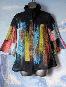 Colorful abstract-patterned shawl or cape with buttons, displayed on a mannequin