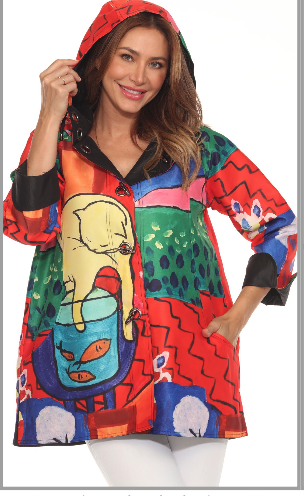 Woman wearing a colorful, patchwork-style hoodie with cartoon-like animal illustrations and abstract patterns, smiling and holding the hood.