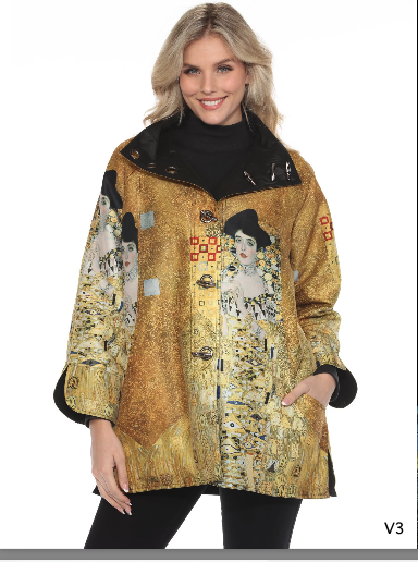 A woman wearing a gold jacket featuring artwork inspired by the artist Gustav Klimt, with a black turtleneck underneath, smiling against a plain white background.